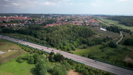 Aerial-panoramic-of-traffic-on-freeway-and-Gdynia-Town-in-background-during-cloudy-and-sunny-day,Poland