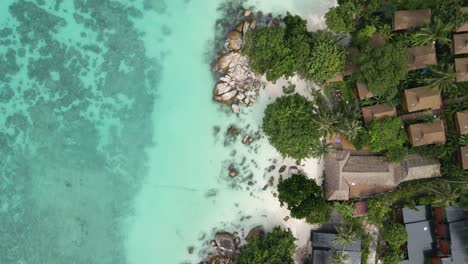 Aerial-top-down-flyover-of-the-coastline-on-Ko-Lipe-Island-showing-both-the-beach-and-homes