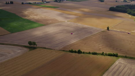 Aerial-backwards-shot-of-agricultural-fields-with-different-pattern-and-colors-during-sunny-day-with-cloud-shades