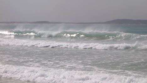 Wave-in-the-sea-breaks-forming-a-tube-and-spreading-water-by-the-wind