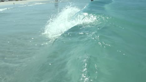 Slow-motion-shot-of-clear-sea-water,-wave-tubing-on-beach,-low-level