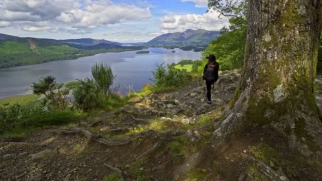 Woman-female-taking-a-photograph-on-a-mobile-phone-View-across-Derwentwater-in-the-English-Lake-District-looking-towards-the-town-of-Keswick-with-Skiddaw-behind