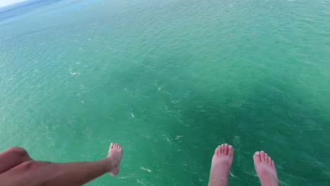 Parasail-b-roll-of-feet-dangling-in-sky-from-2-people-Parasailing-with-green-and-blue-ocean-water-below-them-in-the-Florida-Keys