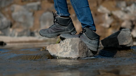 Feet-with-sneakers-crossing-river-stepping-on-loose-stones