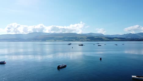 Snowdonia-clear-mountain-range-aerial-forward-view-sunny-calm-Welsh-shimmering-seascape