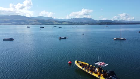 Snowdonia-clear-mountain-range-aerial-view-with-boats-on-sunny-calm-Welsh-shimmering-seascape