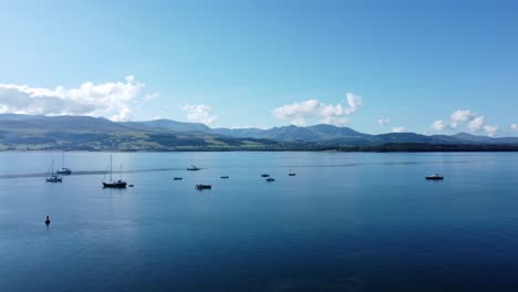 Snowdonia-clear-mountain-range-aerial-rising-view-sunny-calm-Welsh-shimmering-seascape