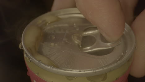 Macro-shot-of-lid-of-soda-can-being-opened-in-slow-motion-and-spilling-cola
