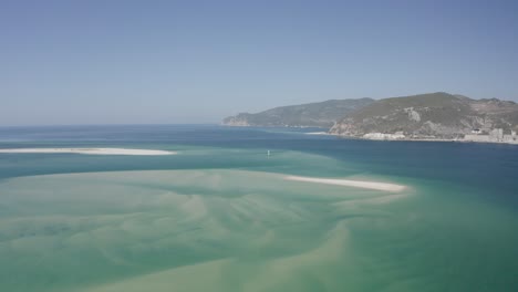 Aerial-view-of-a-tropical-paradise-beach-with-white-sand-and-clear-water-in-Nature-Park-Arrabida-in-Setubal,-Portugal