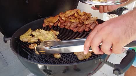 Man-with-steel-clamps-taking-roasted-mushrooms-out-of-charcoal-barbecue-grill