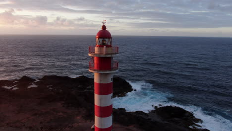 Circling-around-the-beautiful-white-and-red-striped-lighthouse-on-the-rocky-hills-of-Gran-Canaria,-Spain