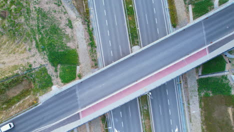 White-van-driving-on-viaduct-over-highway,-aerial-top-down-view