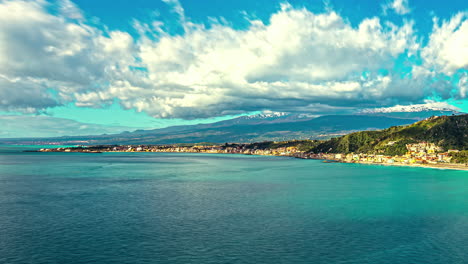 High-angle-shot-of-seaside-town-of-Sicily,-Italy-with-the-view-of-etna-volcano-in-the-background-on-a-cloudy-day-in-timelapse