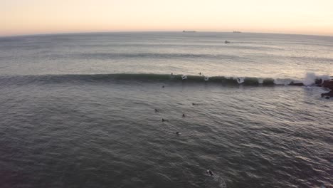 Aerial-drone-view-of-a-group-of-surfers,-waiting-for-waves,-on-coast-of-Portugal