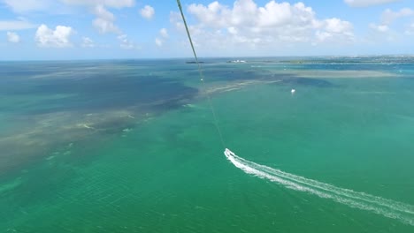 Parasail-b-roll-of-sky-from-2-people-Parasailing-with-green-and-blue-ocean-water-below-them-in-the-Florida-Keys-aerial-footage