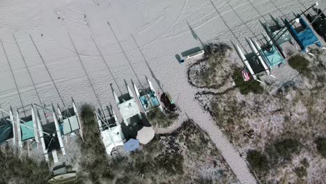 A-Row-of-Small-Waterplane-Area-Twin-Hull-Yacht-on-a-Sandy-Beach-from-an-Aerial-Drone-Shot-Spinning-Fast-While-Looking-Directly-Downward