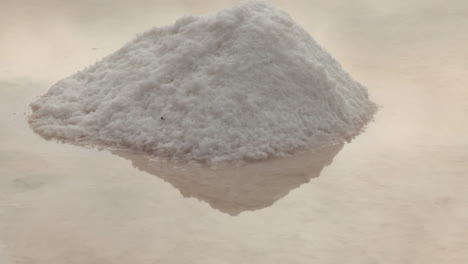 A-small-pile-of-salt-in-the-salt-pans-with-the-reflection-in-the-water-where-it-is-produced