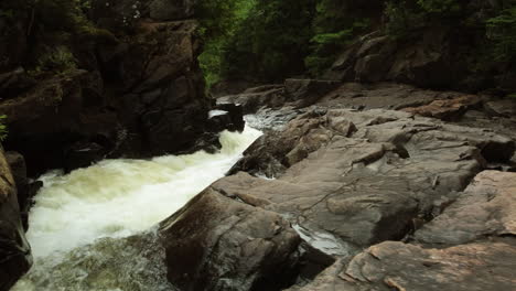 POV-handheld-crossing-river-rapids-rocks-dangerous-water-woodland-day