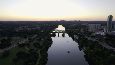 Aerial-view-over-a-ferry-on-the-Colorado-river-in-Austin,-twilight-in-Texas,-USA