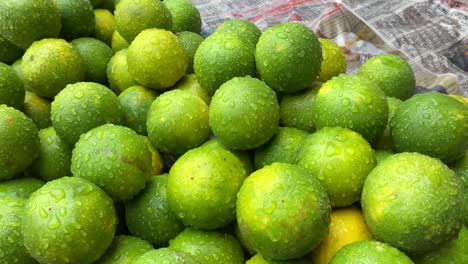 In-Kolkata,-West-Bengal,-a-hardworking-street-vendor-sells-fresh-and-ripe-lemons-at-the-market-along-the-street