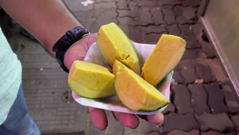 Close-up-top-shot-of-a-man-enjoying-an-Indian-frozen-treat-called-a-mango-kulfi,-which-is-sweet-and-creamy-and-prepared-with-mangoes-instead-of-the-usual-ingredients-in-ice-cream