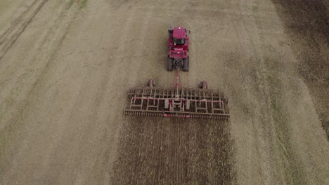 Aerial-orbit-over-the-big-tractor-on-tracks-pulling-harrow-system-to-recultivate-soil-after-the-harvest