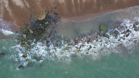 Aerial-footage-moving-left-to-right-along-the-tide-mark-and-sea-defences-at-Happisburgh-beach,-Norfolk