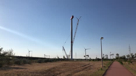 A-wind-turbine-is-being-set-up-by-a-crane-in-Lommel,-Belgium