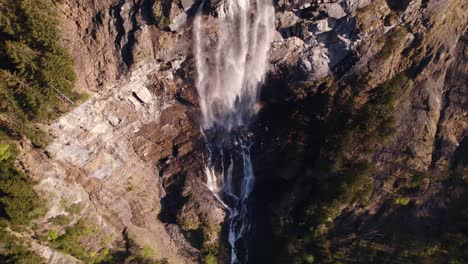 Aerial-drone-footage-raising-up-with-top-down-views-of-a-picturesque-waterfall-in-Grindelwald,-Switzerland