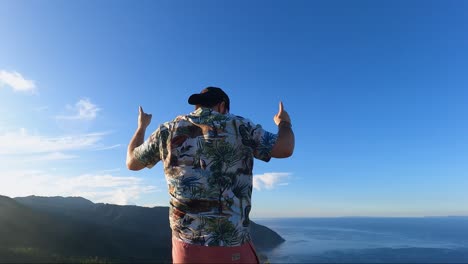 Portrait-Of-A-Happy-Male-Tourist-Dancing-On-Mountain-Park-Facing-Calm-Sea-In-Summer
