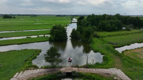 Beautiful-Cinematic-Aerial-Drone-Shot-Following-People-In-a-Small-Boat-on-a-Dutch-Polder