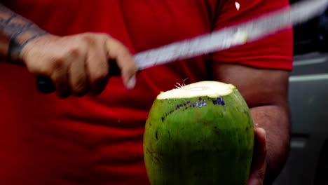 Slow-motion-of-male-hand-with-machete-big-knife-cutting-coconut-from-palm-tree-drinking-fresh-healthy-water