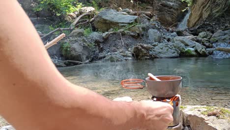 Person-add-wood-to-hobo-cooker-to-cook-soup-in-nature