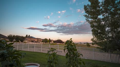 Backyard-garden-at-sunset,-tilt-up-panoramic-movement-to-reveal-the-sky-and-neighborhood---motion-time-lapse