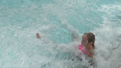 A-little-girl-slides-down-a-steep-kamikaze-slide-and-falls-uncontrollably-through-the-water