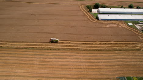 Harvester-working-on-a-field,-aerial-view-from-distance