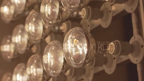 Close-up-shot-of-a-series-of-tungsten-bulbs-on-a-wall-turning-on-and-off-indoors