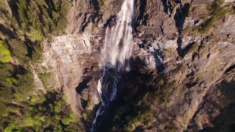 Aerial-drone-footage-pushing-out-and-panning-up-a-scenic-waterfall-in-Grindelwald-in-Switzerland