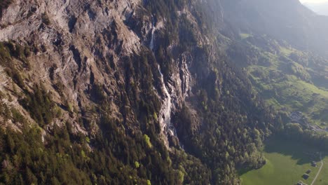 Aerial-drone-footage-pushing-in-and-raising-down-towards-Fallbach,-a-stunning-waterfall-in-Grindelwald,-Switzerland