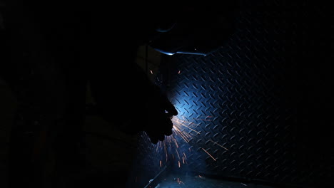 Welding-arc-illuminating-heavy-metal-sheet-blue-as-it-becomes-connected-ready-for-product-delivery
