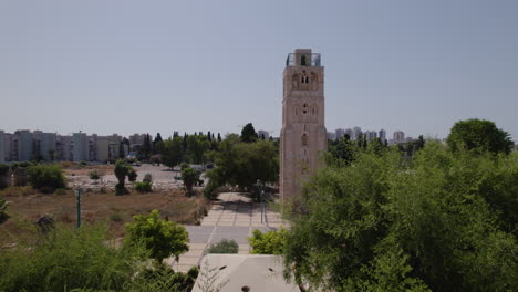The-ruins-of-the-White-Mosque-in-Ramla,-Israel,-revealed-by-a-drone-among-green-trees,-the-minaret-remains-still-standing,-surrounded-by-a-large-square