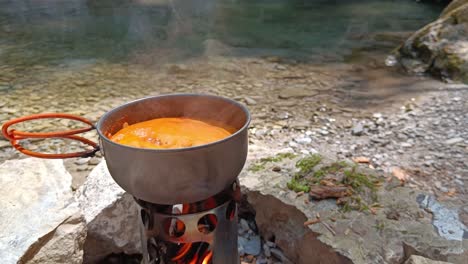 Tomatensuppe-Kocht-Auf-Lagerfeuer-Neben-Fluss-Und-Wasserfall