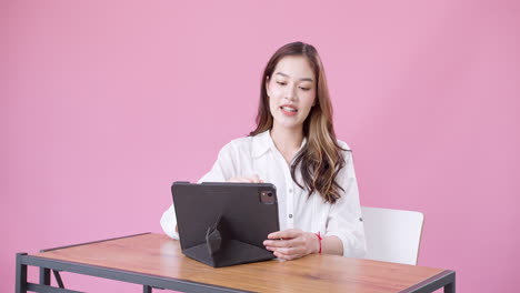 Junge-Asiatische-Frau,-Die-Mit-Einem-Digitalen-Tablet-Büro-Im-Studio-Mit-Rosafarbenem-Hintergrund-Spielt-1