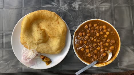 Breakfast-food-from-India-Chole-Bhature,-also-known-as-poori,-is-a-delectable-Indian-meal-cooked-with-all-purpose-wheat-flour-and-eaten-with-chickpea-chana-masala-curry-mixed-pickles-and-sliced-onion