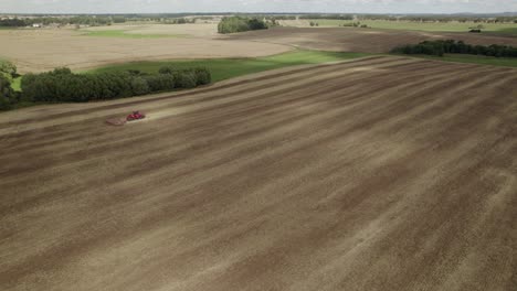 Aerial-shot-big-tractor-on-tracks-pulling-harrow-system-to-recultivate-soil-of-the-big-farm-field---establishing-shot