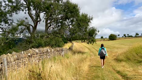 Young-girl-walking-down-a-path-on-the-route-of-the-Cotswolds-Way,-a-long-distance-footpath-in-England
