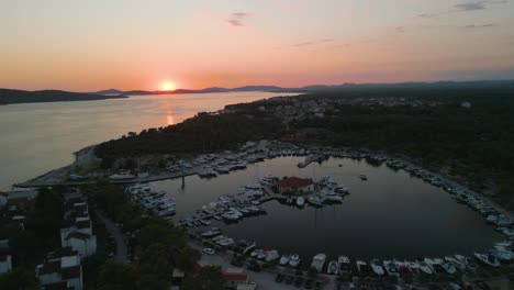Aerial-of-stunning-seascape-at-sunset-with-luxury-sail-boat-yacht-moored-in-dock-harbour-with-scenic-cliff-landscape-in-Adriatic-European-coast