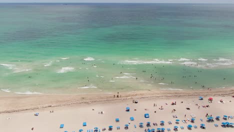 People-enjoy-sandy-beach-and-crystal-clear-ocean-water-on-hot-day-in-Miami
