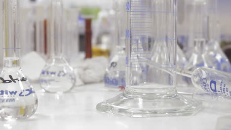 Laboratory-table-full-of-test-tubes-and-beakers-with-clear-liquids---trucking-to-right