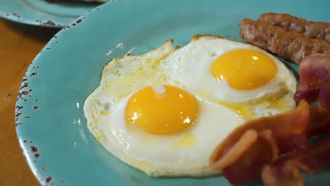 Desayuno-Rico-En-Proteínas-De-Dos-Huevos-Soleados,-Tocino-Crujiente,-Salchichas,-Control-Deslizante-De-Cerca-4k